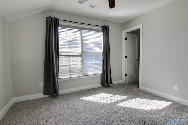 empty room featuring carpet floors, visible vents, baseboards, vaulted ceiling, and a ceiling fan