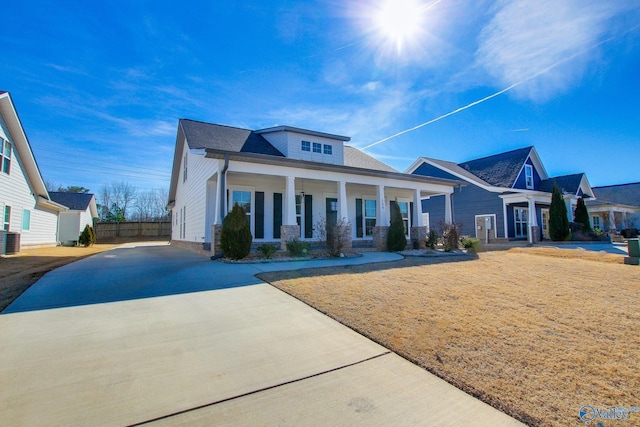 view of front facade featuring fence, a front lawn, a porch, and central AC