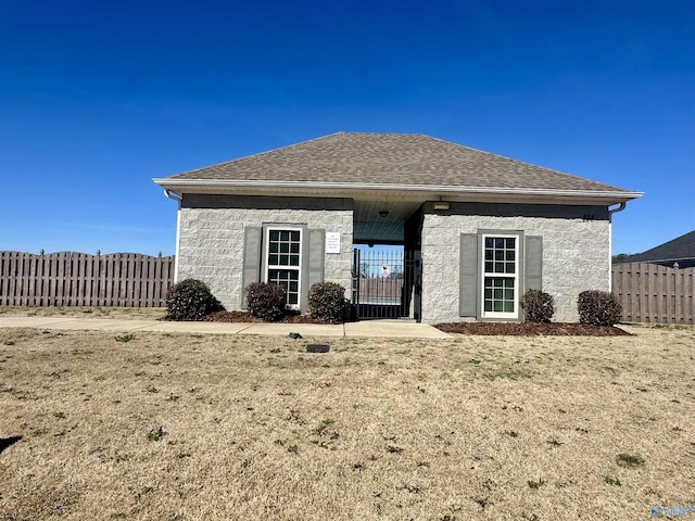 view of front facade featuring a gate, roof with shingles, and fence