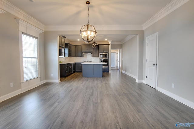 kitchen with dark wood-style floors, stainless steel appliances, light countertops, decorative backsplash, and a sink