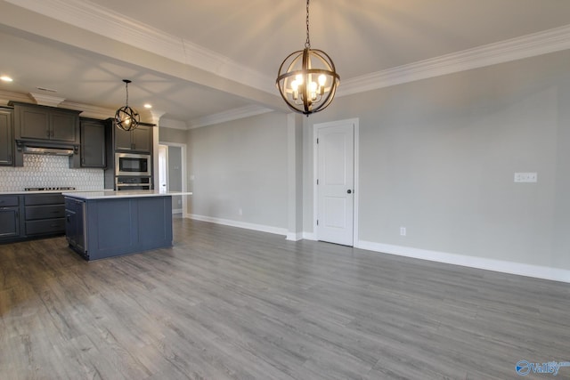 kitchen featuring tasteful backsplash, light countertops, appliances with stainless steel finishes, under cabinet range hood, and baseboards