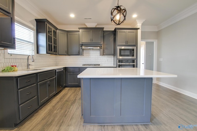 kitchen featuring under cabinet range hood, stainless steel appliances, a sink, light countertops, and a center island