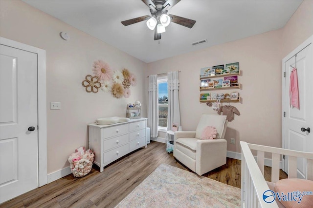 bedroom with baseboards, a ceiling fan, visible vents, and light wood-style floors