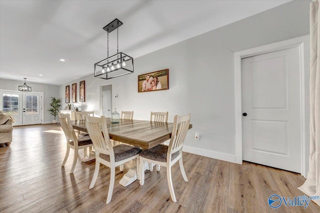 dining space with french doors, baseboards, and light wood finished floors