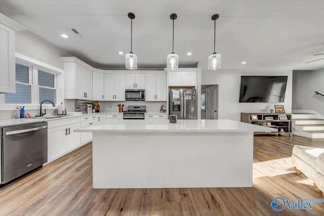 kitchen with stainless steel appliances, light countertops, white cabinets, and a center island