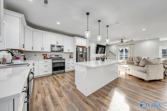 kitchen with appliances with stainless steel finishes, open floor plan, and light countertops