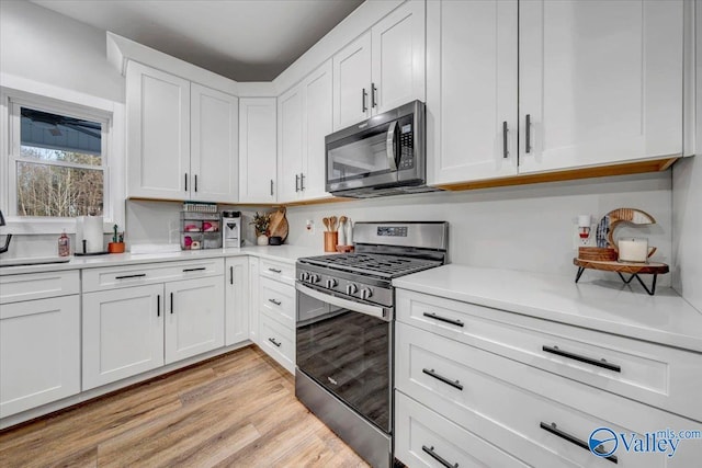 kitchen with white cabinets, light wood-type flooring, stainless steel appliances, and light countertops