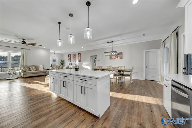 kitchen featuring open floor plan, light countertops, stainless steel dishwasher, and white cabinets