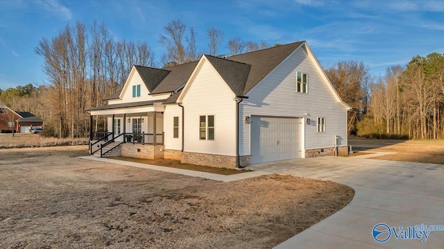 view of side of home with a garage, driveway, and a porch