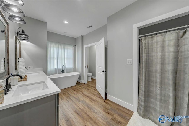 bathroom with a freestanding tub, baseboards, a sink, and wood finished floors