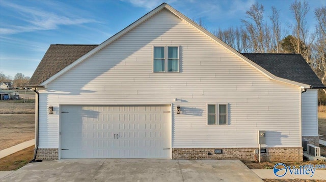 view of side of home with a garage, crawl space, driveway, and roof with shingles