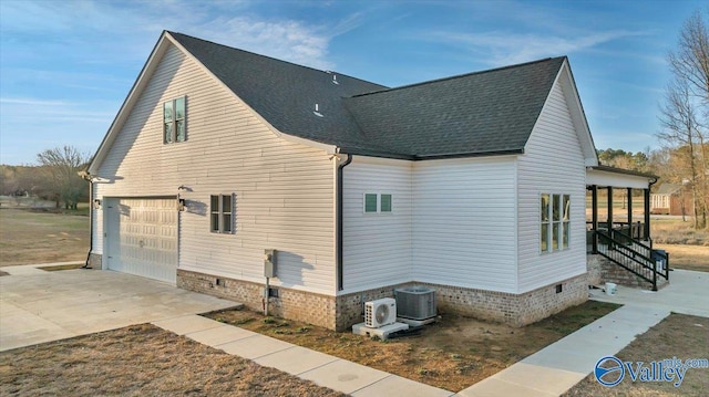 view of side of home featuring driveway, a garage, a shingled roof, central AC unit, and crawl space