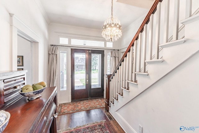 foyer featuring crown molding, dark wood-type flooring, an inviting chandelier, and french doors