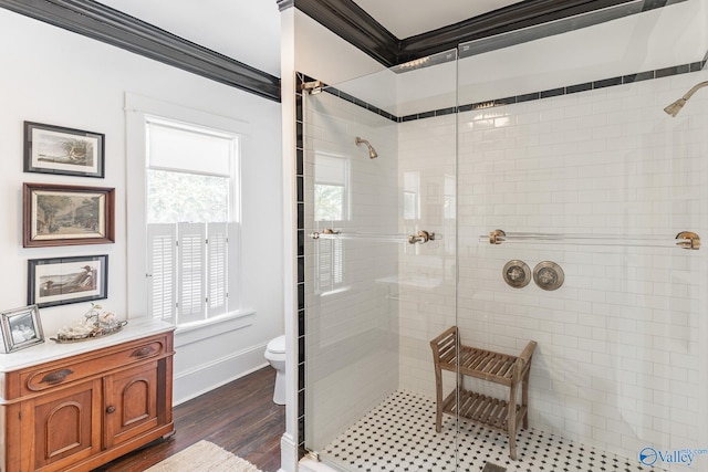 bathroom featuring hardwood / wood-style flooring, tiled shower, ornamental molding, and toilet