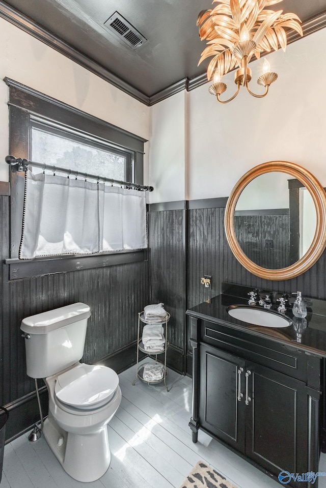 bathroom featuring ornamental molding, toilet, a chandelier, and wood walls