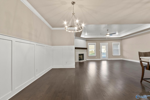 interior space featuring ceiling fan with notable chandelier, a large fireplace, dark wood-type flooring, and a raised ceiling