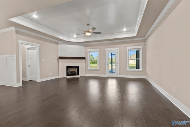 unfurnished living room featuring a tray ceiling, ceiling fan, ornamental molding, and dark hardwood / wood-style floors