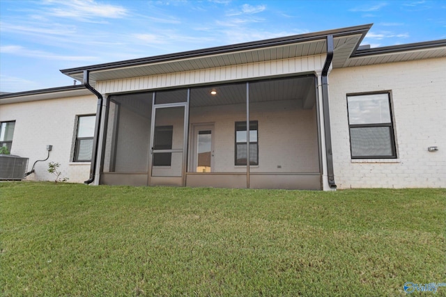 back of house with a lawn, a sunroom, and central air condition unit