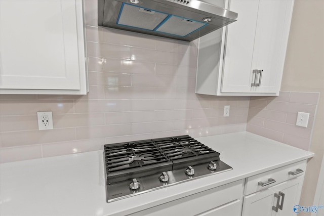 kitchen featuring backsplash, white cabinets, range hood, and stainless steel gas stovetop