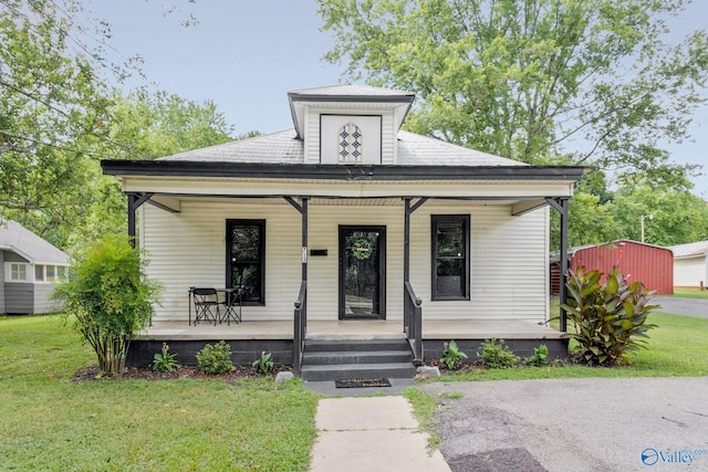 bungalow-style home featuring covered porch, a shingled roof, and a front lawn