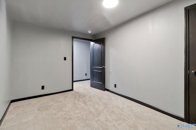 unfurnished room featuring baseboards and light colored carpet