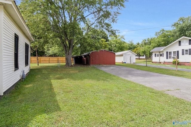 view of yard featuring an outbuilding, fence, and driveway