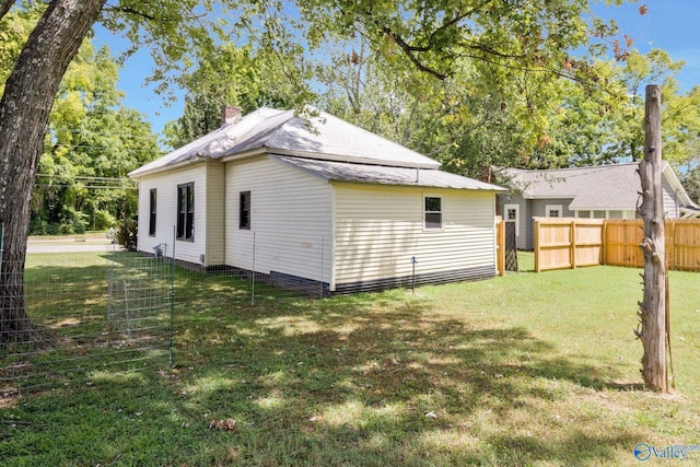 rear view of property with fence, a lawn, and a chimney