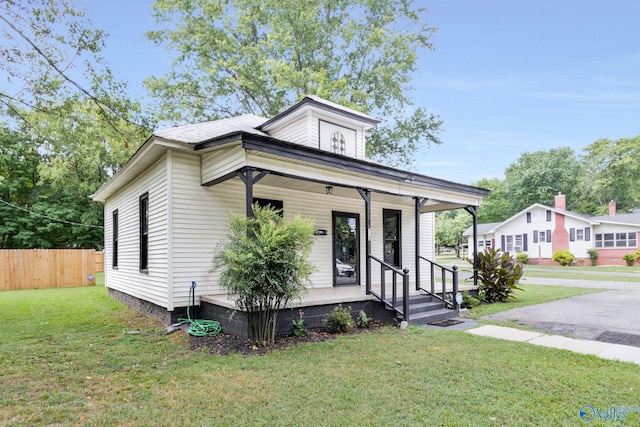 view of front of property with covered porch, a front lawn, and fence