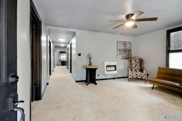 living area featuring ceiling fan, heating unit, baseboards, and light carpet