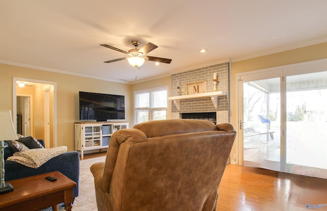 living room featuring crown molding, a fireplace, light hardwood / wood-style floors, and ceiling fan