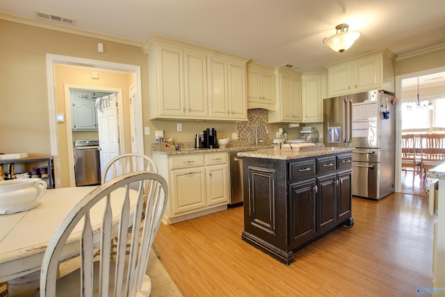 kitchen with a center island, light hardwood / wood-style flooring, ornamental molding, appliances with stainless steel finishes, and light stone countertops