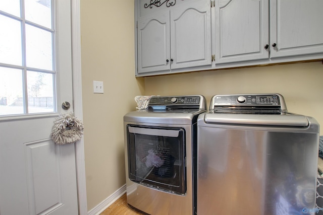 clothes washing area featuring cabinets, separate washer and dryer, and light hardwood / wood-style flooring