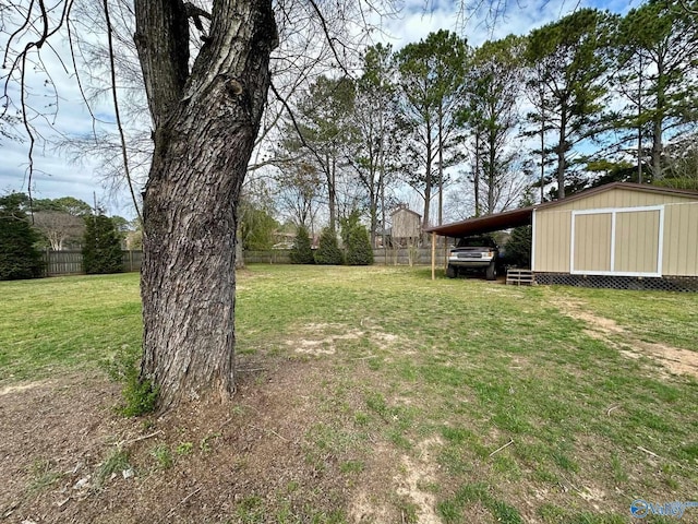 view of yard with fence, an outdoor structure, an attached carport, and a shed