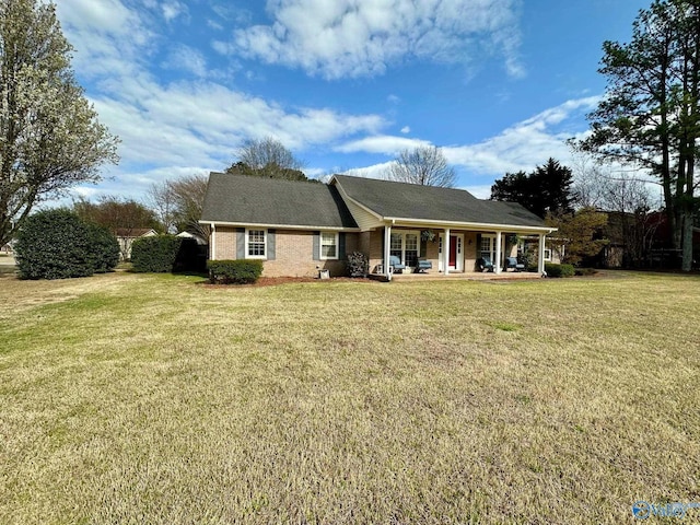 rear view of property with a lawn, covered porch, and brick siding