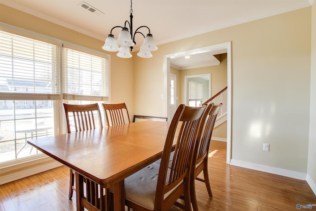 dining space with crown molding, a chandelier, and light hardwood / wood-style floors