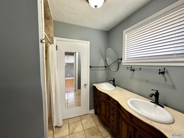 bathroom featuring double vanity, tile patterned flooring, and a textured ceiling