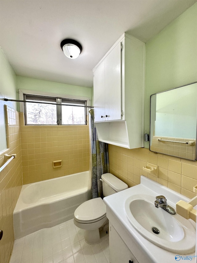 bathroom featuring toilet, tile patterned flooring, shower / bath combo with shower curtain, vanity, and tile walls