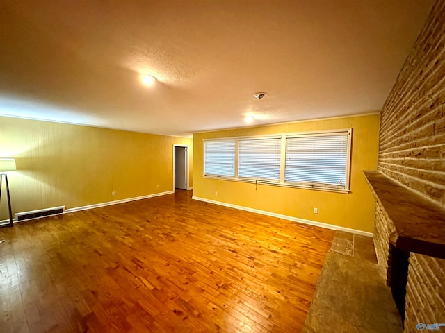 unfurnished living room featuring brick wall and wood-type flooring