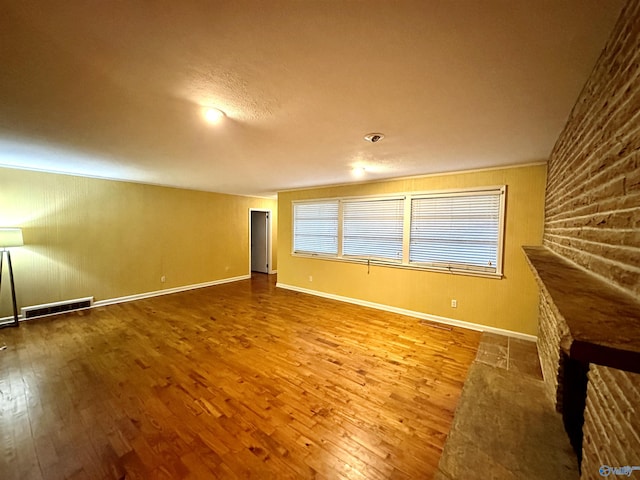 unfurnished living room featuring wood finished floors, visible vents, and baseboards