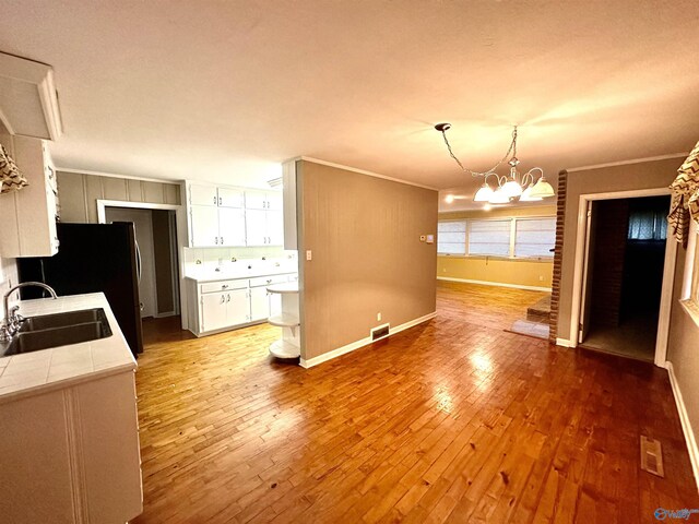 kitchen with tile counters, sink, light wood-type flooring, and an inviting chandelier