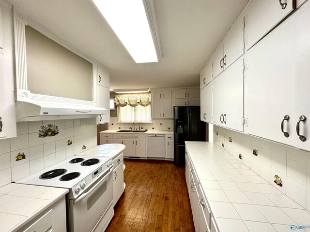 kitchen with tile counters, white appliances, dark wood-type flooring, backsplash, and sink