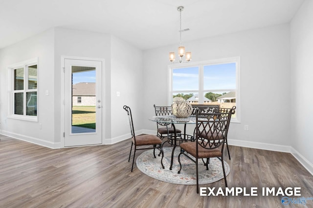 dining space with baseboards, wood finished floors, and an inviting chandelier