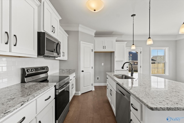 kitchen featuring a kitchen island with sink, sink, appliances with stainless steel finishes, decorative light fixtures, and white cabinetry