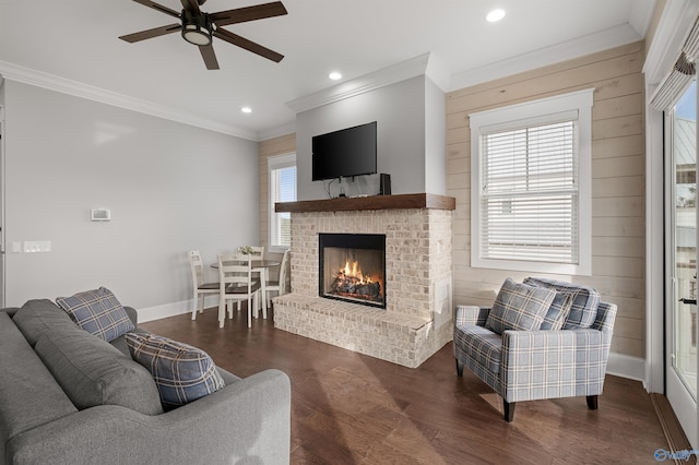 living area with recessed lighting, wood finished floors, baseboards, a brick fireplace, and crown molding