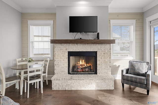 living room with a brick fireplace, crown molding, wooden walls, and wood finished floors