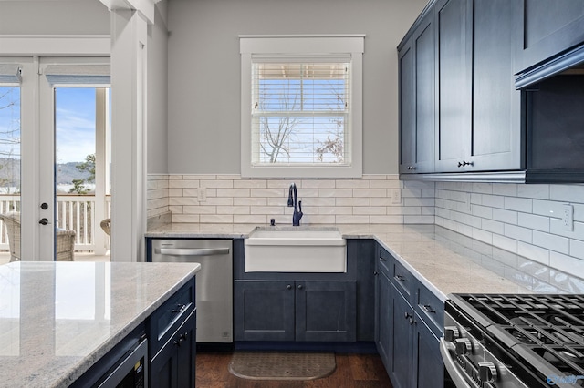 kitchen featuring tasteful backsplash, appliances with stainless steel finishes, light stone counters, and a sink