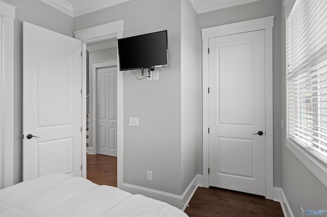 bedroom with dark wood-style floors, crown molding, and baseboards