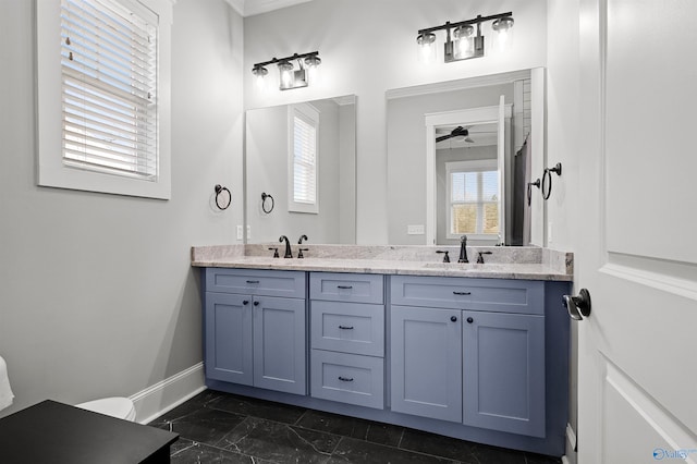 bathroom with marble finish floor, a sink, baseboards, and double vanity