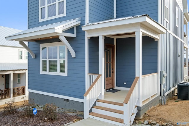 doorway to property with covered porch, metal roof, central AC unit, and crawl space