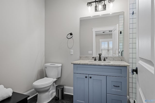 bathroom featuring toilet, baseboards, and vanity